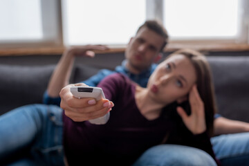 selective focus of man near woman holding remote controller from air conditioner while feeling hot