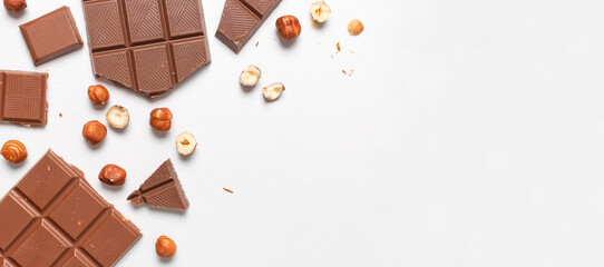Bar and pieces of milk chocolate, hazelnut on white background flat lay top view copy space....