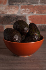fresh avocados in a red bowl