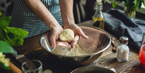 A woman is preparing fresh dough in a cozy atmosphere. Concept of cooking delicious dough dishes at home.
