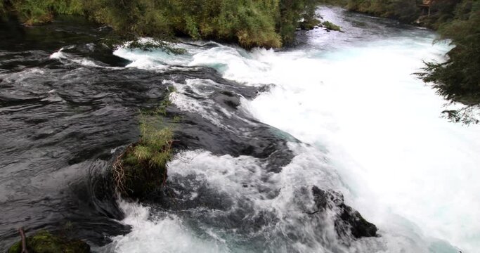 The wild white waters of Caburgua River flowing down and jumping at Carileufu waterfall. An amazing scenery inside the south of Chile rainforest at Pucon, an idyllic landscape for some relax time
