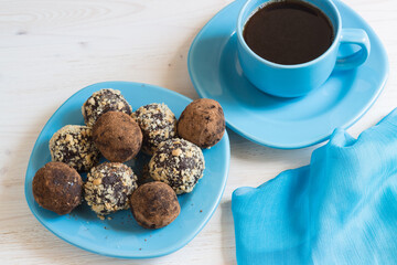 A portion of homemade energy balls and a Cup of black coffee on a blue wooden table. Delicious, healthy dessert. Lifestyle.