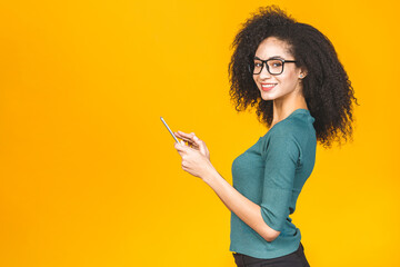 Isolated young american student girl with curly african hair holding digital tablet and smiling standing over isolated yellow background with copy space for text, logo or advertising.