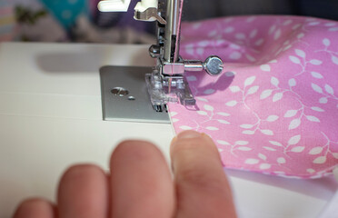 Selective focus on handmade pink fabric cotton face mask in sewing process. Protection against saliva, coronavirus, cough, dust, pollution, virus, bacteria, COVID-19, coronavirus.