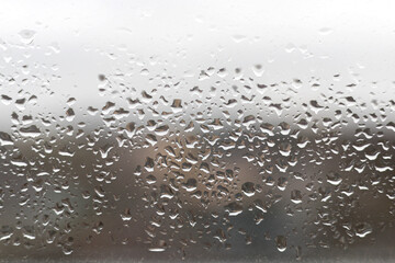 Close-up of water drops on the window glass. Rain drops on glass. Blurry backdrop, background, wallpaper, texture