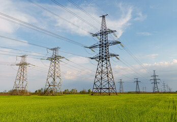 Electrical net of poles on a panorama of blue sky and green meadow
