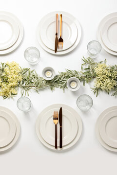 Wedding dinner table setting decorated with fresh flowers and greenery
