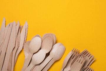 Disposable wooden cutlery on yellow background. Single use biodegradable eco-friendly disposable...