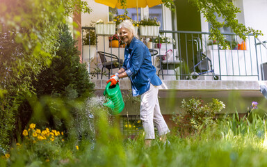 Senior woman watering plants in her garden  © pikselstock
