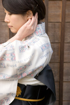 うなじに手をやる和服姿の女性