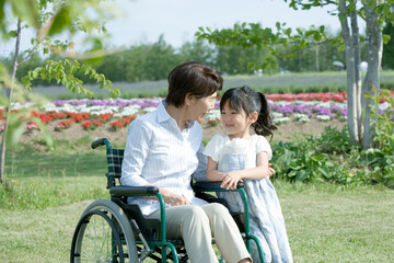 孫と散歩をする車いすの60代女性
