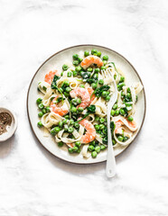 Delicious lunch - green peas, shrimps, spinach, cream sauce tagliatelle pasta  on a light background, top view