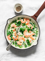 Seafood sauce for pasta. Fresh green peas, shrimps, spinach, cream sauce in a cooking pan on a light background, top view