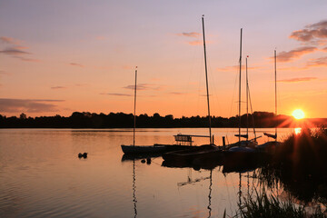 tranquil lake scene with sail boats at sunset