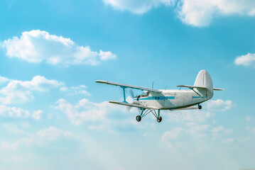 Fototapeta na wymiar Small old private plane flying in light white clouds