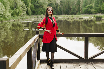 Georgian woman in red national dress with cross symbols. Attractive woman on the lake. Georgian...