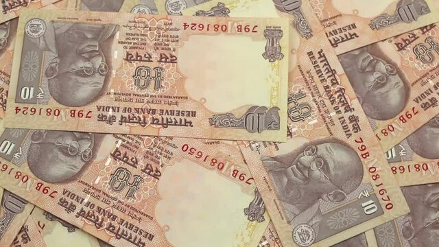 A video of ten rupee bank notes from India, close up, rotating in a circle