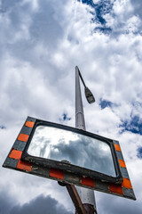 Traffic mirror on a lamp-pole under dramatic sky