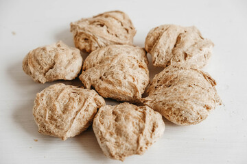 Raw dehydrated soy meat or soya chunks on a white wooden background. Copy, empty space for text