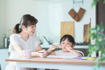 Fototapeta premium ダイニングテーブルでお絵かきをするお母さんと娘