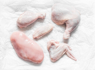 Pieces of raw butchered chicken - legs, thighs, breast, wing on a light background, top view. Raw food ingredients for cooking