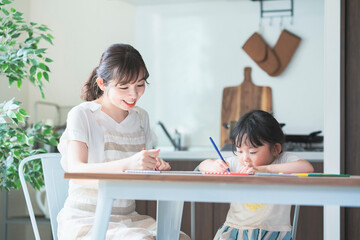 ダイニングテーブルでお絵かきをするお母さんと娘