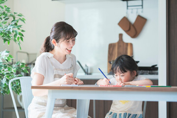 ダイニングテーブルでお絵かきをするお母さんと娘