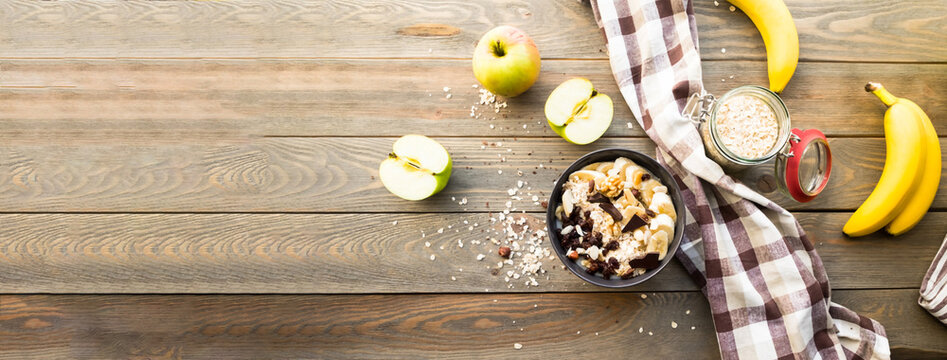Colorful breakfast. Oatmeal with fruit and chocolate on a wooden background with tulips. Summer equinox or Hello summer concept. Close-up