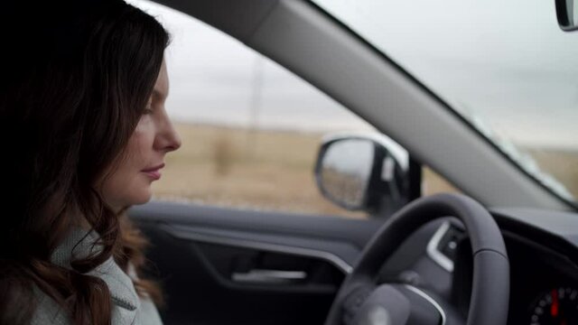 Brunette woman driver behind the steering wheel driving her crossover suv car