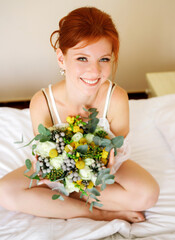 Obraz na płótnie Canvas Portrait of a red-haired bride with a bouquet in her hands. Morning of the bride.