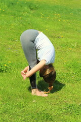 Young woman of European appearance does yoga in summer nature