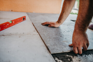 skilled worker installing the ceramic wood effect tiles on the floor Worker making laminate flooring on the construction site of the new apartment