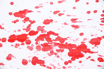 Drops and splashes of red paint on white background close-up.