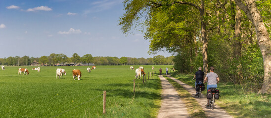 Panorama of a couple riding their bicycle at a dirt road in Overijssel, Netherlands