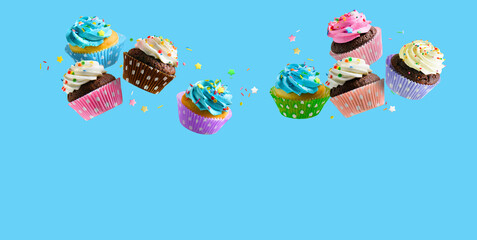 Cupcakes with pink white and blue cream and colorful sprinkles flying over blue background. Copy...