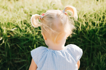 little blonde girl with two ponytails in summer. High quality photo