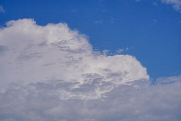 White light fluffy clouds in a blue sky with a solar flare.