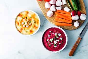Set of classic hummus and beet hummus appetizers with carrot, radish, tomato and cucumber