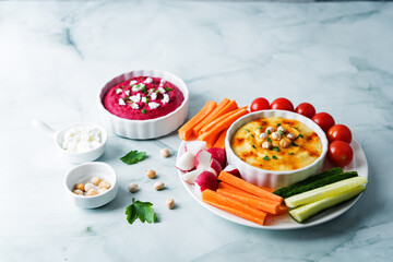 Set of classic hummus and beet hummus appetizers with carrot, radish, tomato and cucumber