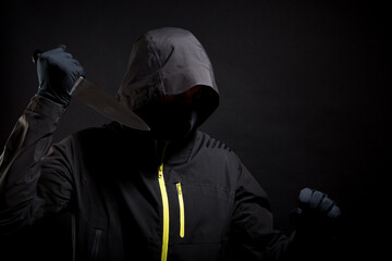 Masked thief is trying to scare you with raised arms isolated on black background