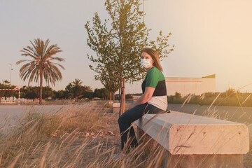 Woman portrait on a mask in the nature. New normal. Post quarantine sunset and social distancing