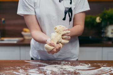 girl kneads dough on a wooden table in the kitchen
