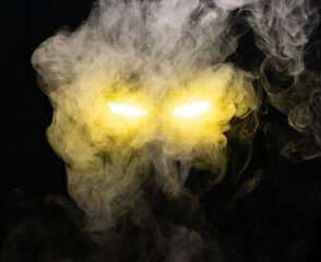 Ominous luminous eyes staring out of the darkness illuminate with a beam of yellow light swirling white smoke