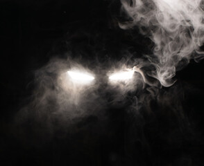 Ominous luminous eyes looking out of the darkness illuminate the swirling smoke with rays of white light