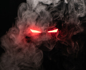 Ominous luminous eyes staring out of the darkness illuminate with rays of red light swirling white smoke