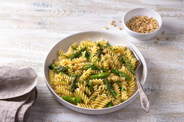 Vegan pasta with asparagus, garlic, pine nuts and parsley on a wooden background, top view. simple homemade food