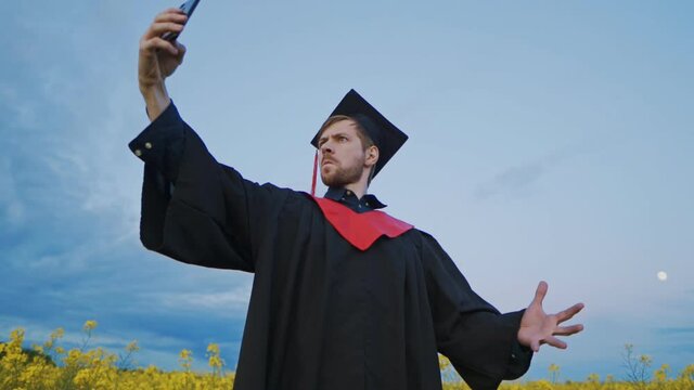 Excited graduate takes funny selfies on smartphone in Park