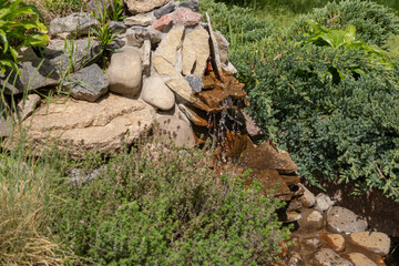 Alpine slide with stones, various ornamental plants and a waterfall