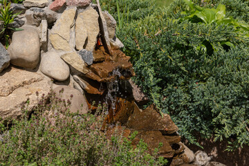 Alpine slide with stones, various ornamental plants and a waterfall