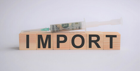 wooden cubes with the inscription import on a white background, with a syringe with dollars, banknote, business concept
